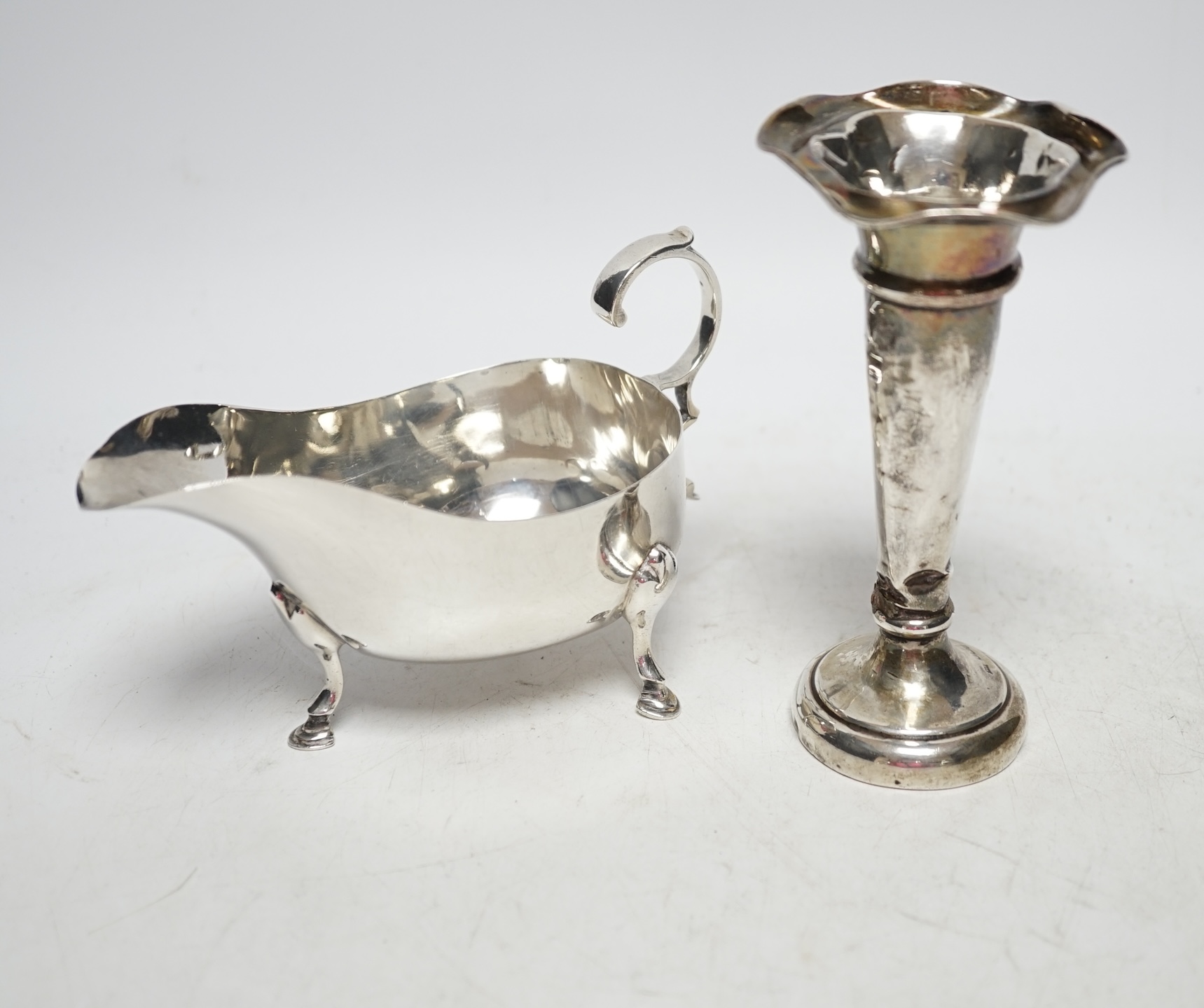 A George V silver sauceboat, Sheffield 1925, 14.5cm, 4.2oz and a similar silver mounted posy vase. Fair and poor condition.